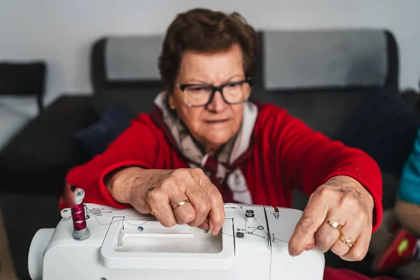 Sewing craftswoman with glasses threading threads on sewing machine