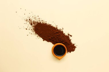Bir fincan kahve. Eskimiş fincanın düz düzeni bej arka planda kahve ile dolu. Fincanın etrafına kahve tozu..
