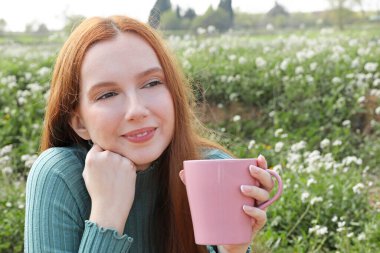 Güzel bir kadın bir fincan kahve içerken manzarada rahat görünüyor.