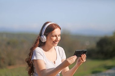 Kulaklıklı genç bir kadın telefonuyla video konferansı yapıyor.