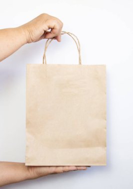 Bir kadın, beyaz arka planda fotokopi alanı olan kahverengi bir kese kağıdı tutuyor. Teslimat hizmeti konsepti. Ellerini kesekağıdına koy, kapat..