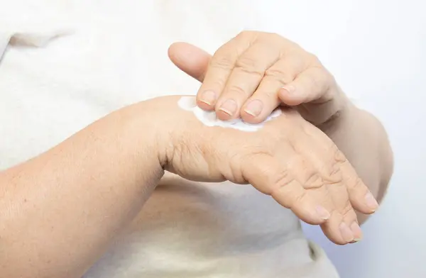 Yakın plan. Eline krem sürerken günlük rutinini yapan olgun, orta yaşlı bir kadın. Yaşlanma önleyici cilt bakımı. Spa tedavileri