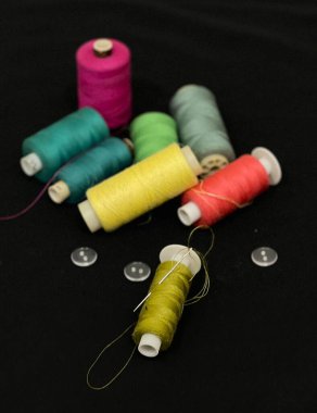 Dikiş için aletler, iğneler, bobbin. Alan çerçevesini dikiş araçları ve aksesuarlarla siyah arkaplanda kopyala. 