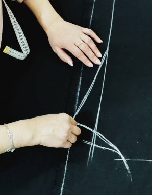 Dikiş atölyesindeki terzi kadın. Kıyafet yapma süreci. Tekstil kumaşının yüzeyine yakın çekim ve dikiş aletleri. 