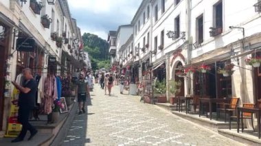 Güney Arnavutluk 'un Cirokaster kenti. UNESCO 'nun miras şehri Cirokaster' daki eski çarşı bölgesinde karakteristik bir cadde. Turistler el sanatları dükkanlarını ziyaret ediyor