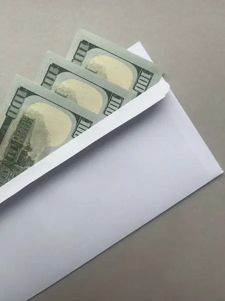 Money in a white envelope. Saving money. Three new hundred dollar bills.