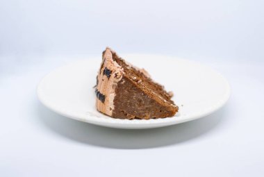 Beyaz tabakta çikolata ve krema olan bir parça pasta..