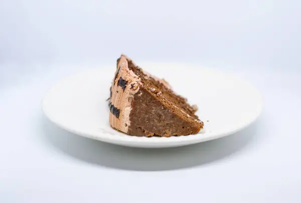 Beyaz tabakta çikolata ve krema olan bir parça pasta..