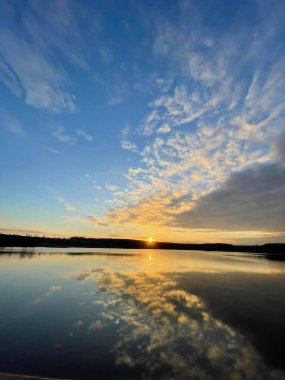 Gölün üzerinde akşam, güneş batıyor, göldeki bulutların yansıması.