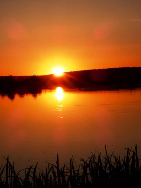 Akşamları ufuktan süzülen turuncu güneş göle yansıyor.