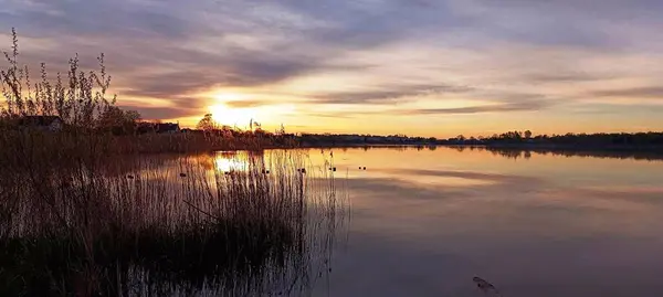 Gölün üzerinde batan güneşin görüntüsü.