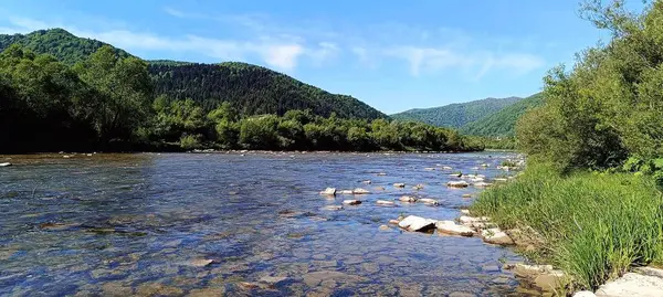 Yeşil dağların arasında taşlı nehrin fotoğrafı.