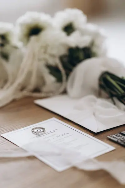 Düğün detayları: alyanslar, davetiyeler ve çiçek aranjmanları.