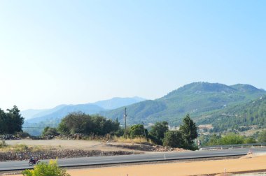 Dağları ve yolu olan Türk manzarası. Çalılar ve yeşil çimenler. Mavi gökyüzü. Metin ve seyahat tasarımlarınız için boşluk.