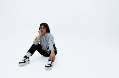 Üzgün görünümlü genç bir kız sıkılıyor. Moda kıyafetleri içinde oturuyor. Mesaj için yer var. Müzik dinliyormuş. Üzüntü ve yalnızlık.