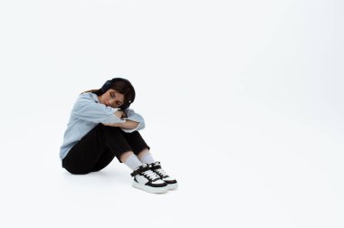 Üzgün görünümlü genç bir kız modaya uygun giysiler içinde oturur. Mesaj için yer var. Müzik dinliyormuş. İzole edilmiş. Üzüntü ve yalnızlık.