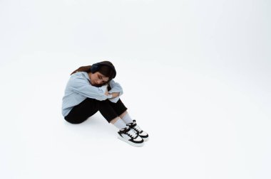 Üzgün görünümlü genç bir kız modaya uygun giysiler içinde oturur. Mesaj için yer var. Müzik dinliyormuş. İzole edilmiş. Üzüntü ve yalnızlık.