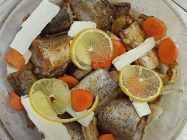 Cam bir kabın içinde taze çiğ balık, limon dilimleri, tereyağı ve havuç. Üst görünüm ve metin için boşluk kopyala. Ev yapımı yemek. Sağlıklı beslenme, diyet, vejetaryen. Kapat.