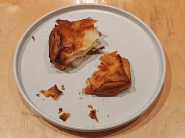 Tahta bir masada beyaz bir tabakta gevrek çörek parçaları. Kırıntılarla. Yatay olarak. Mesaj için yer var. Kafe ya da restoran reklamı. Dizinin bir parçası.