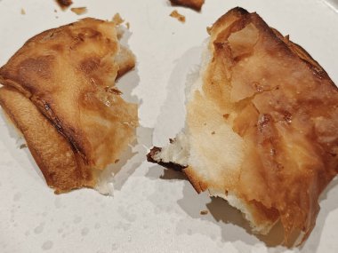 Tahta bir masada beyaz bir tabakta gevrek çörek parçaları. Kırıntılarla. Yatay olarak. Mesaj için yer var. Kafe ya da restoran reklamı. Dizinin bir parçası.