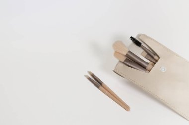 Arka planda makyaj malzemesi poşeti var. Glamour makyaj sanatçısı kesesi ve çıplak bej güzellik ürünleri. Düz yerde, üst tarafta. Yatay, izole