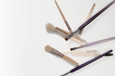 Makyaj, çıplak, bej, mor fırçalar kaotik bir şekilde beyaz arka plana yerleştirilmiş. Çeşitli profesyonel güzellik fırçaları. Makyaj aletleri. Üst Manzara. Güzellik uzmanları ve kozmetologlar için içerik.