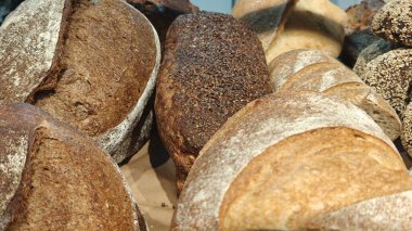 Fırında ya da bakkalda mayasız ekmek ekmeği. Alışveriş vitrininde taze pişmiş, yakın plan. Beyaz ve kahverengi ekmek somunları. Yatay