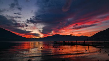 Kırmızı, mor, turuncu renklerle gölde muhteşem bir gün batımı.