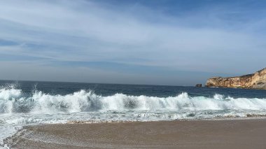 Bulutlu bir günde dalgalı güzel bir sahilin dikey görüntüsü.