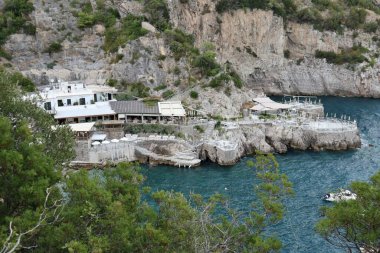 Marina del Cantone - 4 Eylül 2023: Conca del Sogno restoranı, bitişik otel ve lidoyla, günbatımında Recommone Körfezi 'nde.