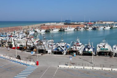 Termoli, Molise, Italy  12 April 2024: The port of Termoli, close to the Borgo Antico, characterized by a pier for fishing boats and the Guardia di Finanza, an intermediate pier for boarding for the Tremiti Islands, and the shipyard pier at the north clipart