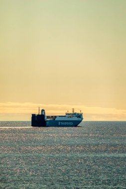 Büyük bir gemi, doğanın güzelliği ile çevrili engin ve geniş bir su kütlesinin yüzeyinde görkemli bir şekilde yüzüyor.