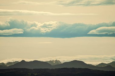 The sky is overcast with clouds above, and majestic mountains can be seen rising prominently in the background of this view clipart