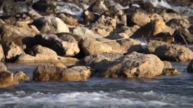Sahil boyunca benekli görkemli kayaların sakin ve resimsel bir görüntüsü, yumuşak dalgaların hafifçe okşadığı.