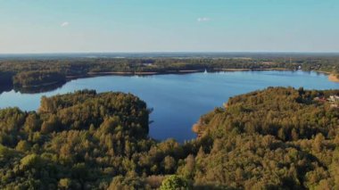 Sersemletici hava manzarası hayat dolu, canlı ve bereketli ormanlarla dolu sakin bir gölü güzel bir şekilde gösteriyor.