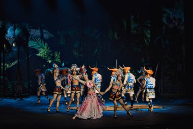 Canlı bir grup insan aydınlanmış bir sahnede güzel bir şekilde dans ediyor, yeteneklerini ve sanatsal ifadelerini sergiliyorlar.