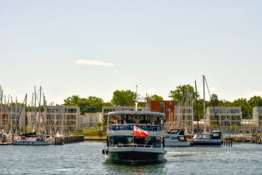 Canlı ve canlı bir marina, çeşitli tekneler ve modern binalar sergileniyor, hepsi de güzel, berrak bir gökyüzünün altında.