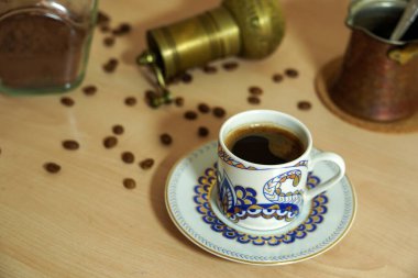 Ahşap zemin üzerinde fasulye olan bir fincan Türk kahvesi.