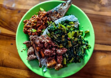 Lezzetli bir Endonezya yemeği ızgara balık, pirinç, tofulu yeşil fasulye ve ahşap masada baharatlı sambal.