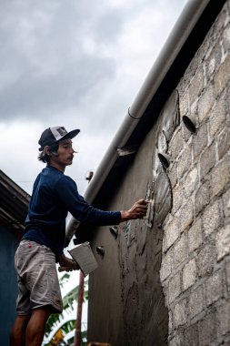 Baubau, Endonezya, 15 Haziran 2024 - Duvarı yenileyen bir zanaatkar