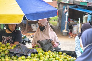 Endonezya, 5 Ekim 2024 - Müşteriler geleneksel Endonezya pazarından tatlı portakal (Citrus aurantium) seçiyorlar