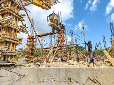 Endonezya - 5 Ekim 2024 - İnşaat işçileri inşaat sütunları oluşturuyorlar - inşaat işçileri güneşli bir günde inşaat alanında beton sütunlar inşa ediyorlar.