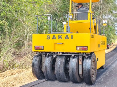 Baubau, Indonesia, November 30, 2024 - Road Construction: A Sakai Pneumatic Tyred Rollers Compacts Asphalt in a Rural Area. clipart