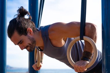 Yetişkin bir adam dışarıda halka üzerinde jimnastik yapıyor. Spor konsepti.