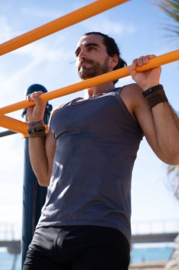 Parktaki egzersiz çubuğunda barfiks çeken bir adam. Jimnastik konsepti.