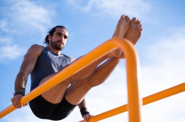 Sakallı bir jimnastikçinin paralel barlarda oturduğu düşük bir görüntü. Jimnastik konsepti.