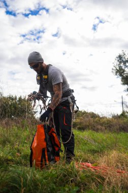 Ağaç budama ve ağaç bakımı için ip ve ekipman hazırlayan bir ağaç ustası.