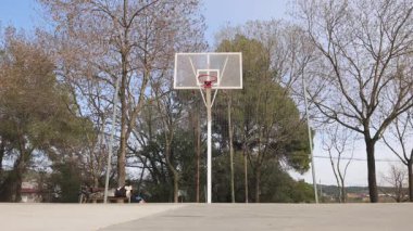 Genç adam, arkadaşının basketbol smaç basmasına yardım ediyor.