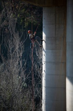 Köprü sütunu üzerinde çalışan halat erişim teknisyeni bakım veya teftiş için demirleme yerleri kuruyor