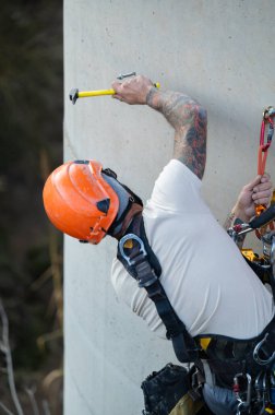 Endüstriyel tırmanışçı beton bir yapının bakım çalışmaları sırasında bir cıvata çekiçleme